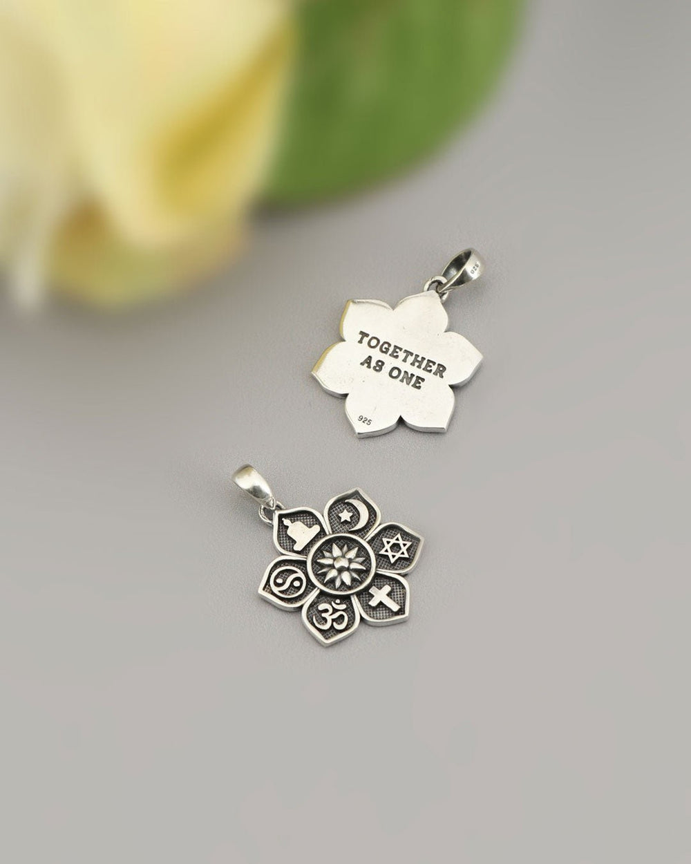The sterling silver Coexist pendant, front and back: seven symbols on the front, 'Together as one' engraved on the back