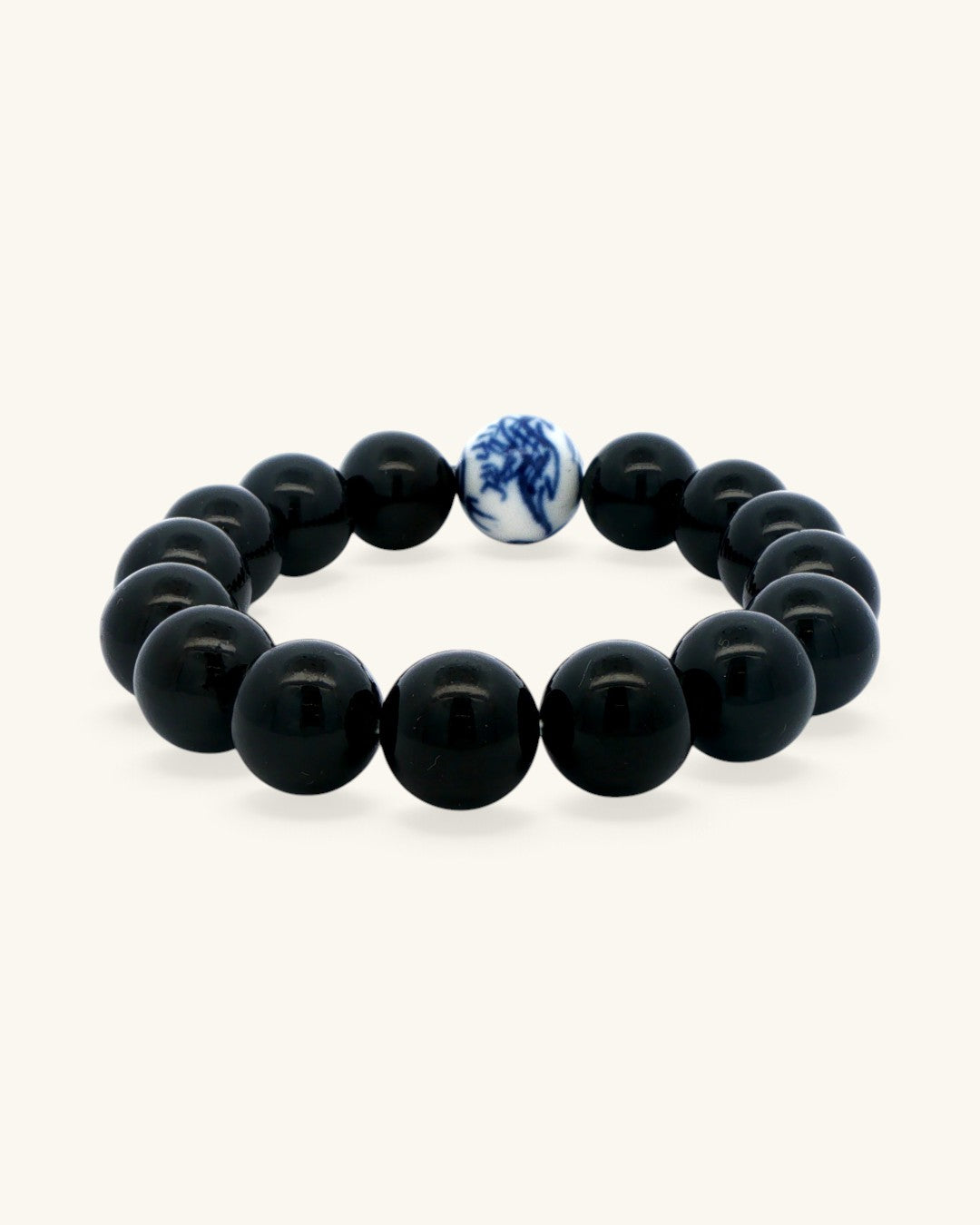 Black obsidian bead bracelet at an angle, glossy 12 mm beads with the porcelain bead at the top