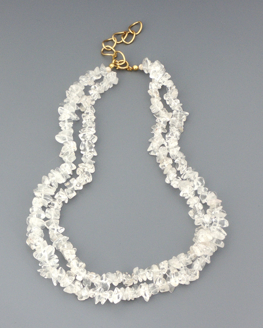 Clear quartz chip necklace, double strand laid out on grey showing the full length and gold tone clasp