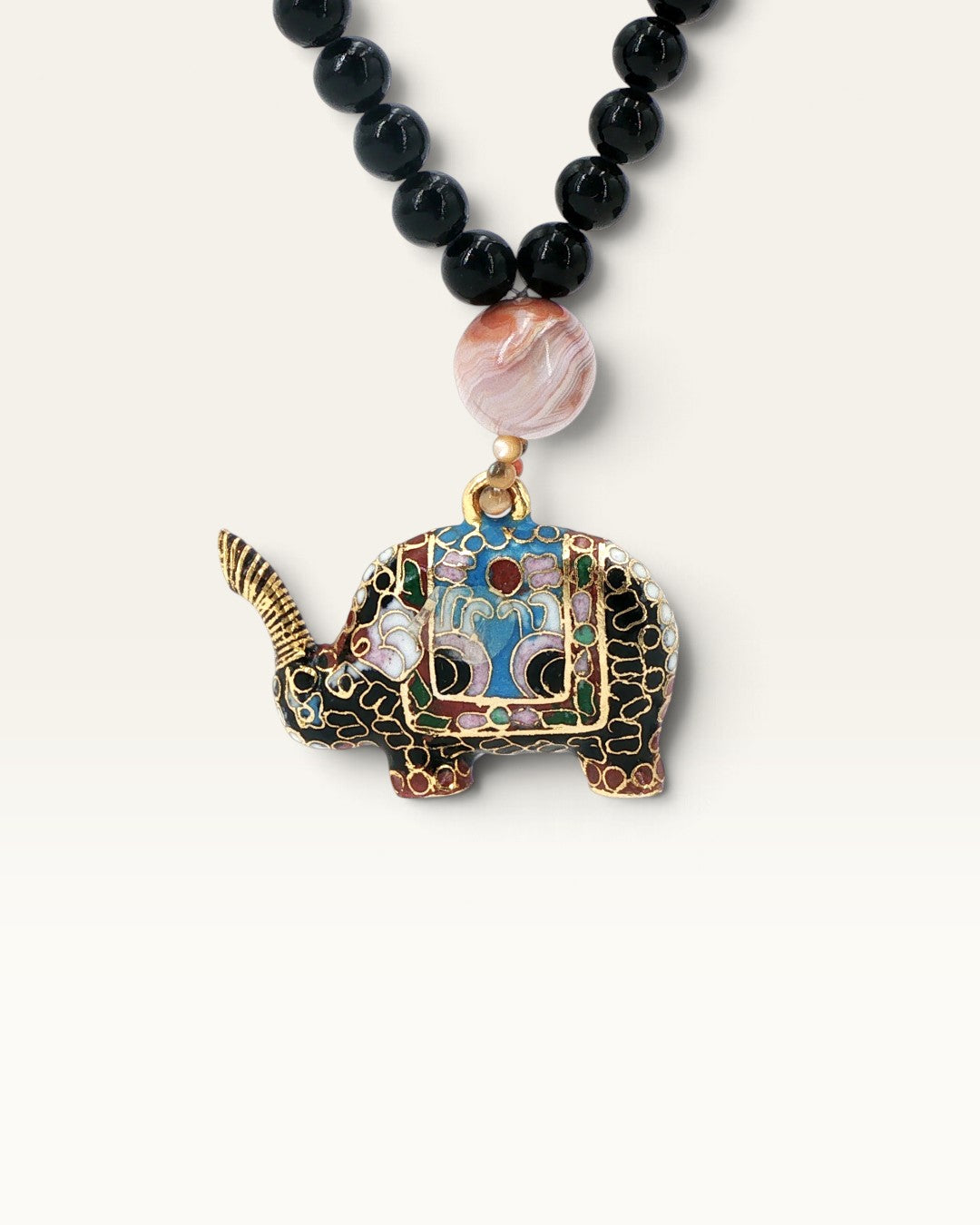 Close-up detail of cloisonne elephant pendant with multicolor enamel and banded agate bead on black stone bead necklace