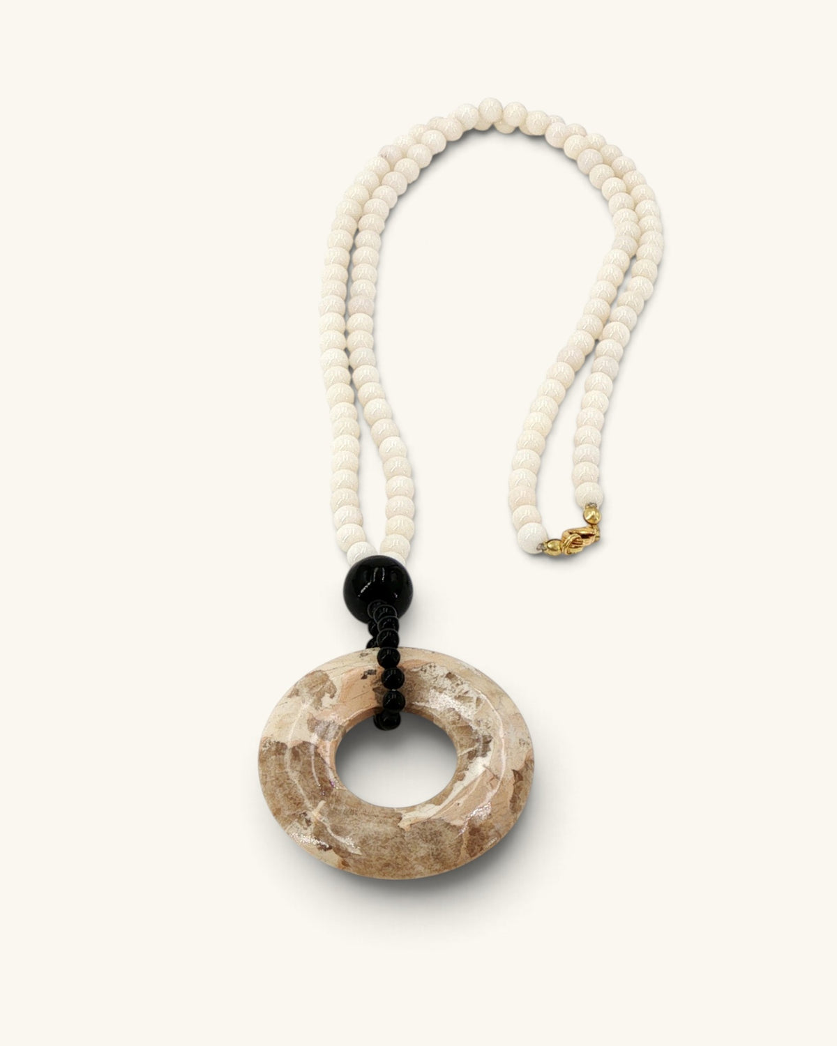 Mother of pearl bead necklace laid flat on white, full strand with the brown jasper donut pendant